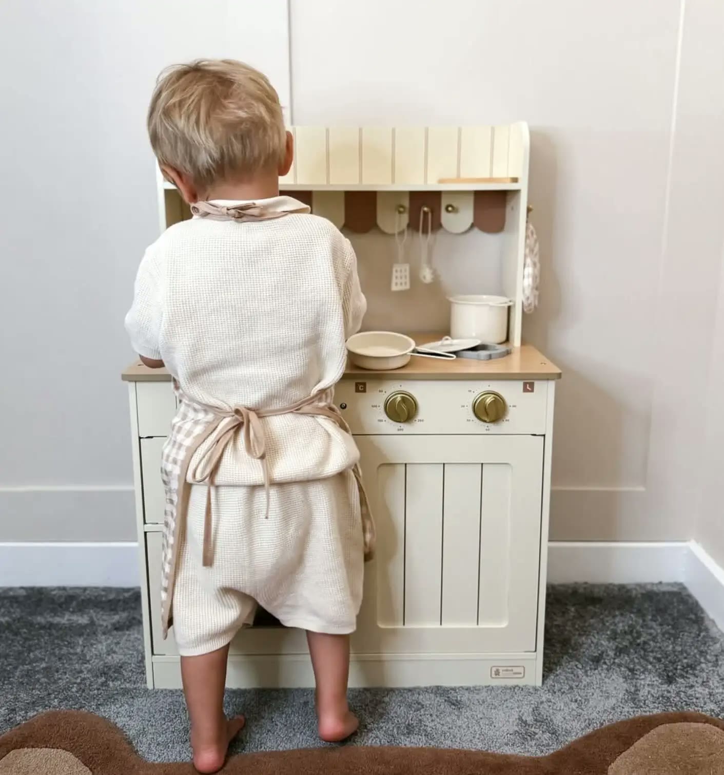 Barababy lifestyle product photograph of a child playing at a cream wooden play kitchen