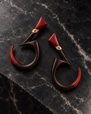 W.Ritzdorf sculptural dark earrings with red accents in a product photograph on veined black stone